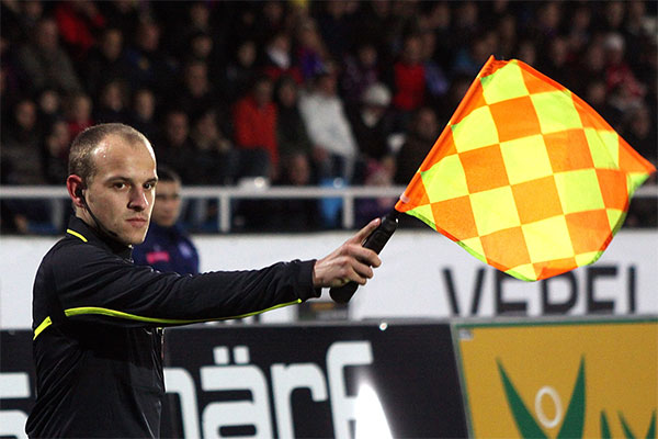 A linesman signals for offside by raising his flag.